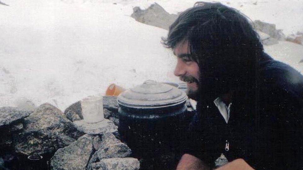 An old photo of Pete Thexton smiling in front of a camp stove