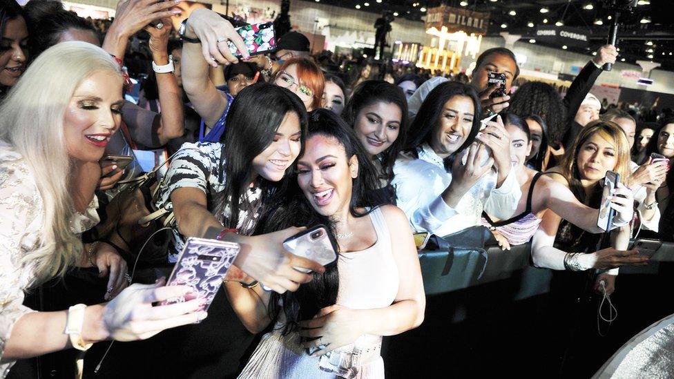 Beauty influencer Huda Kattan poses with fans at BeautyCon