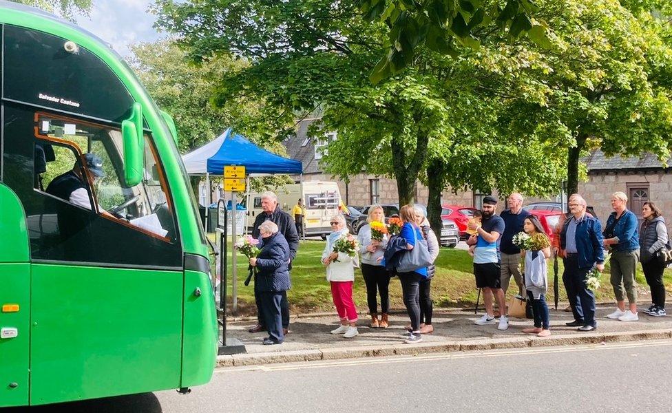 People queuing for bus with flowers