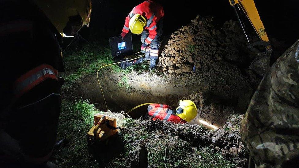 Firefighters excavating pipe