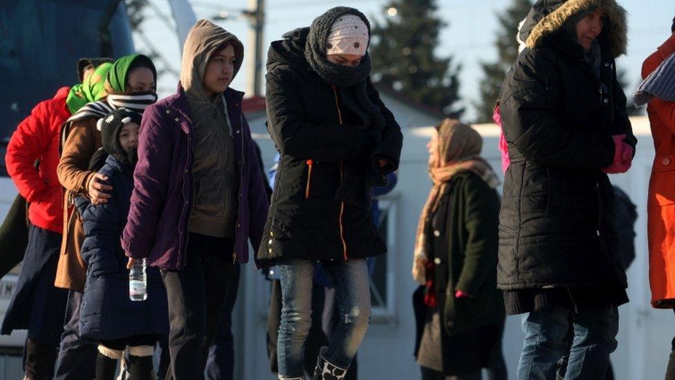 Migrants and refugees queue to receive food as they wait to cross the border from Greece to Macedonia