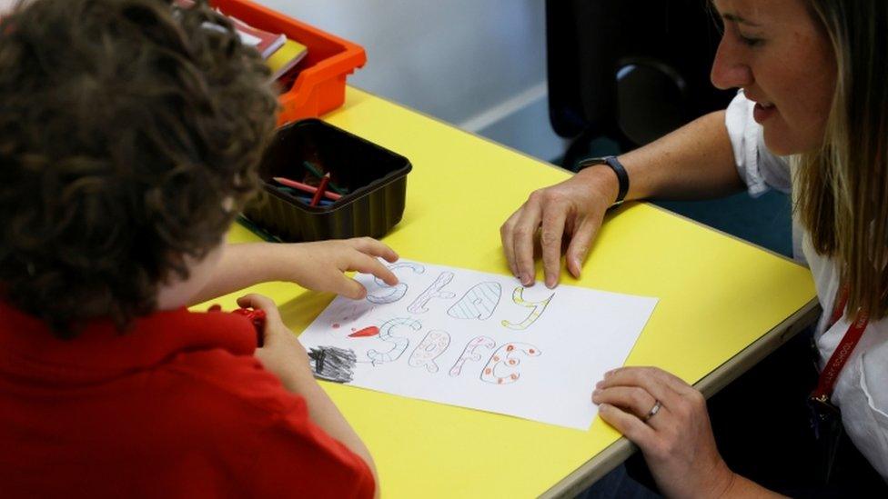 A child sitting in a classroom making a poster