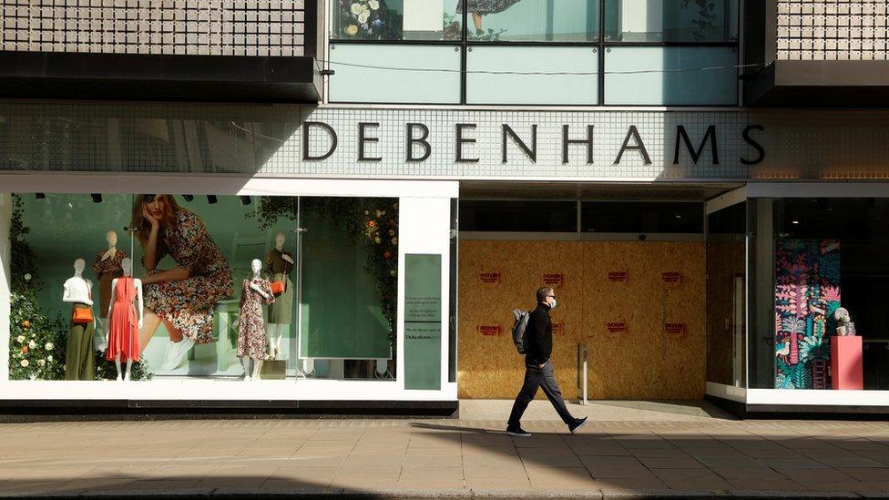 Man walking past a Debenhams store