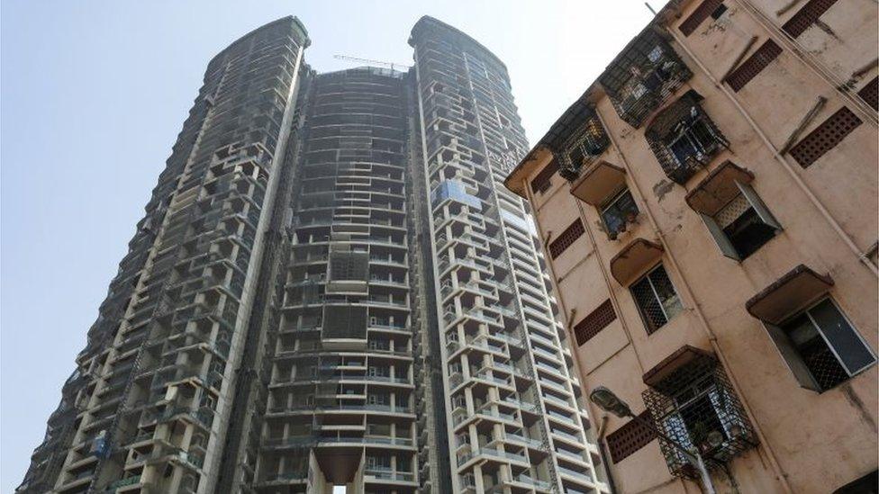 An under construction high-rise residential tower is pictured behind an old residential building in Mumbai, India, February 8, 2016.