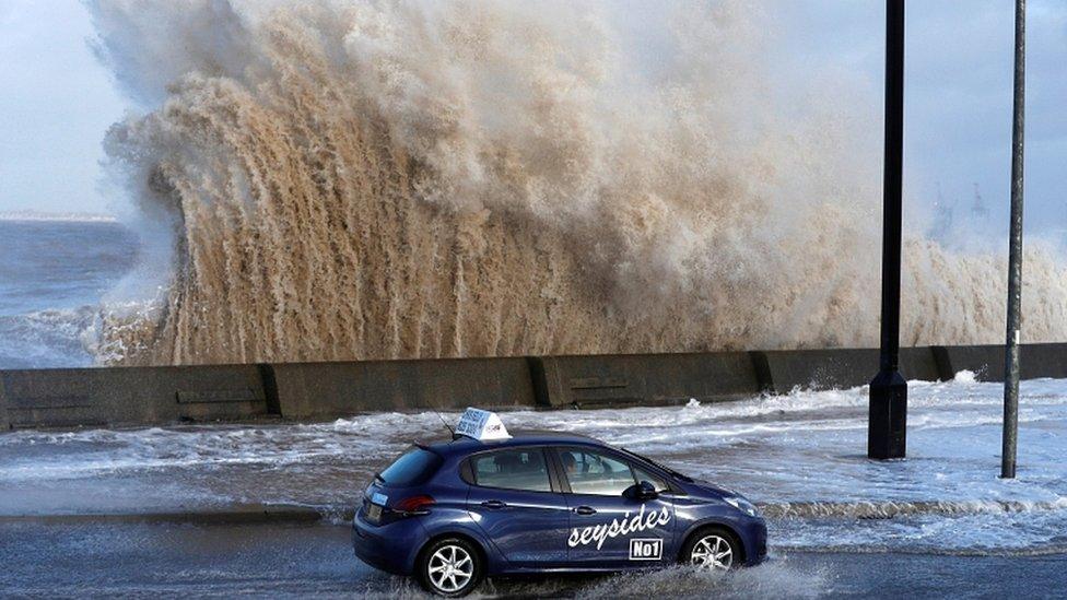 A car drives along a flooded road in New Brighton, on the coast of the Wirral peninsula, in Merseyside, Britain, January 3, 2018.