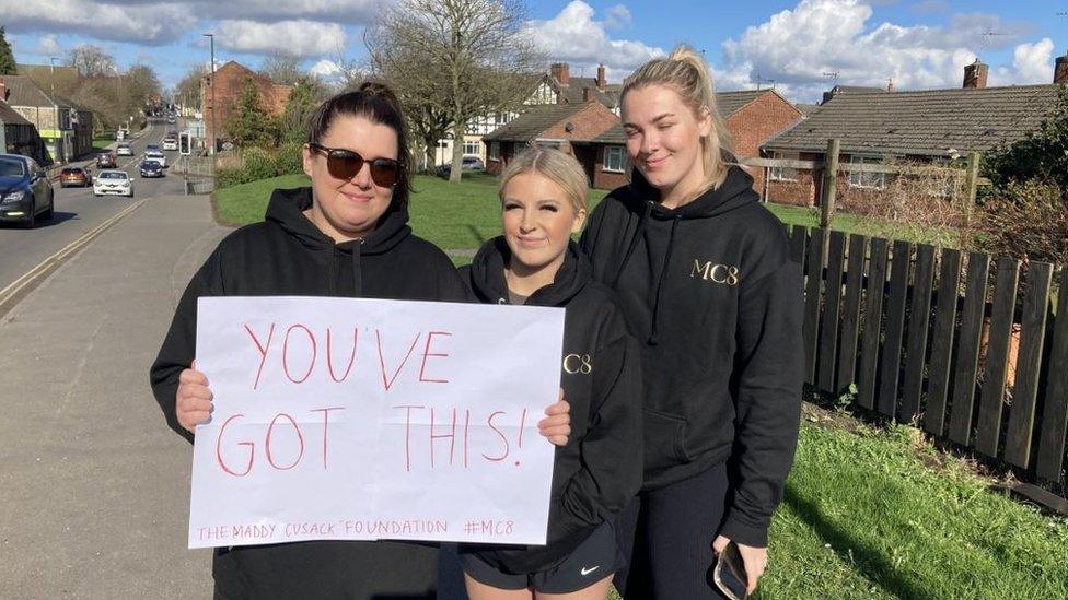 Walkers hold up a sign reading 'You've got this'