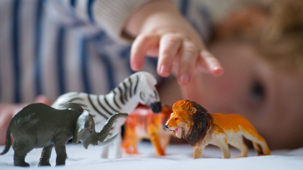 Child playing with toy animals