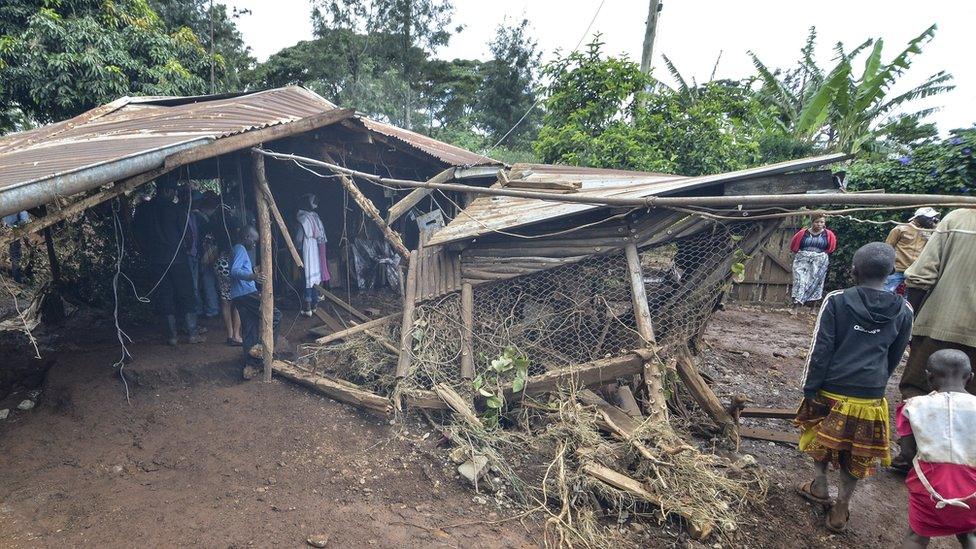 Residents walk next to a house destroyed by water that leaked from Petal dam after bursting its banks near the town of Solai, in Nakuru County on 10 May 2018.