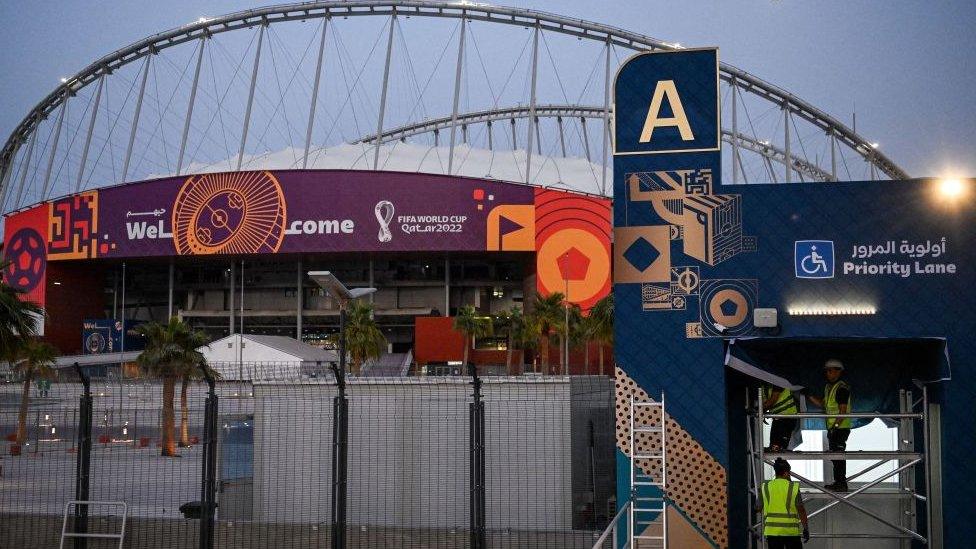 Workers stand at an entrance of the Khalifa Stadium in Doha.