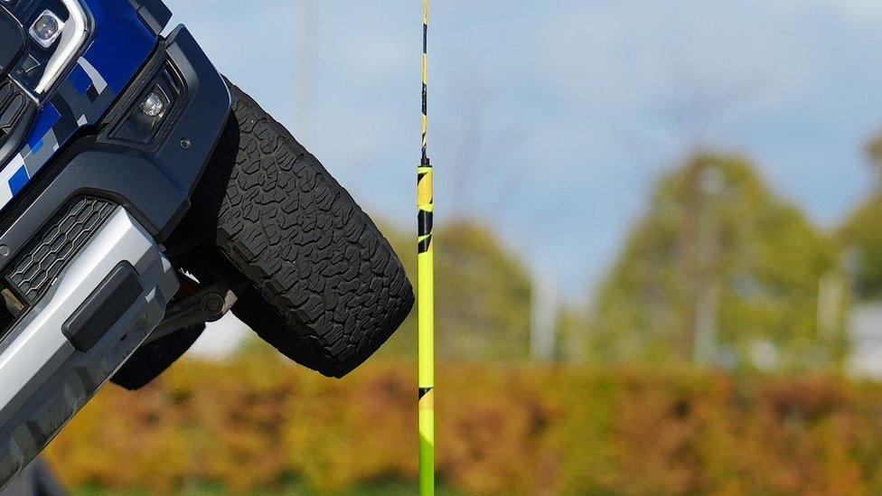 Close up of a wheel tilted into the air passing by a yellow pole