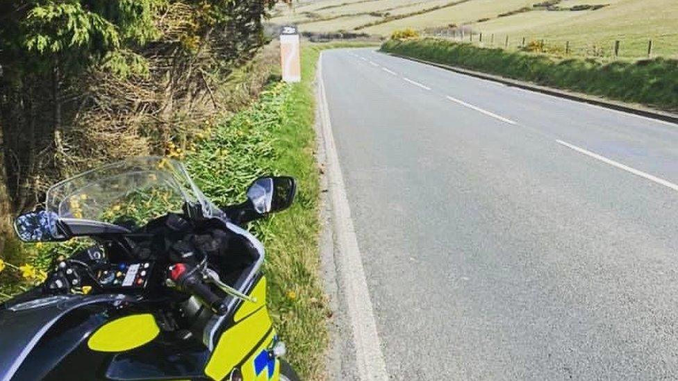 Police motorbike parked next to a clear road