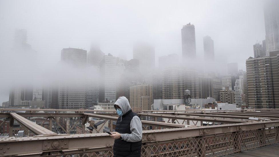 A man wearing a mask walks the Brooklyn Bridge in New York City.