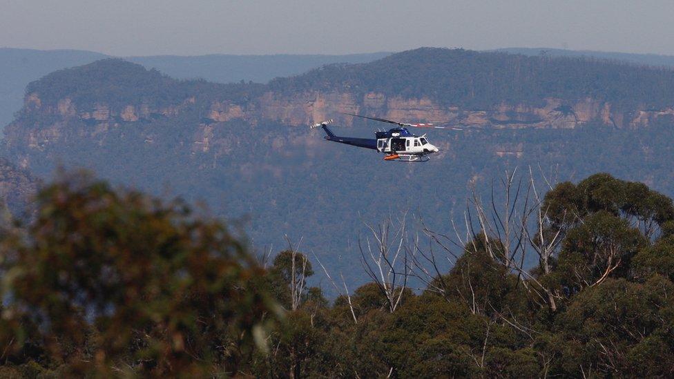 A New South Wales police helicopter retrieves the bodies of a father and son from a walking track where a landslide killed two and injured two others at Wentworth Falls in the Blue Mountains