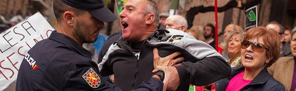 A protester is held back by a policeman at Madrid's High Court where Rodrigo Rato, former chairman of rescued bank Bankia and former head of the International Monetary Fund answered allegations of misusing company credit cards on 16 October 2014 in Madrid, Spain