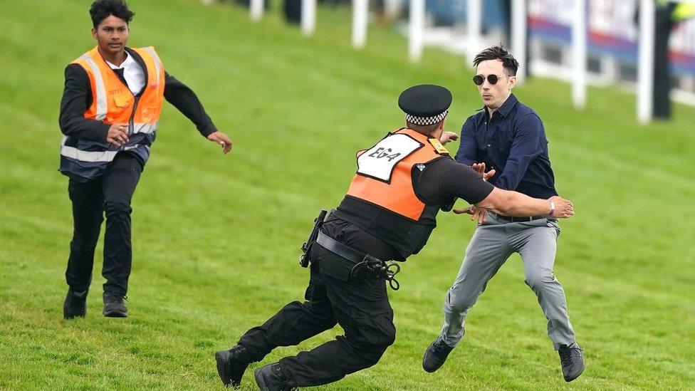 A protester is tackled by police and stewards during the Derby at Epsom Downs Racecourse, Epsom