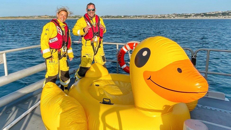 RNLI crew member with Quackers the inflatable duck on board a lifeboat