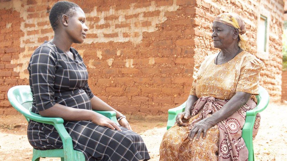 Birth attendant and pregnant woman talking outside the house