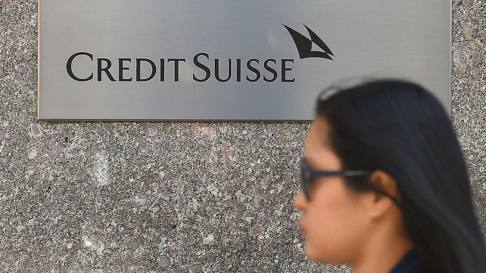 Woman walking past Credit Suisse bank