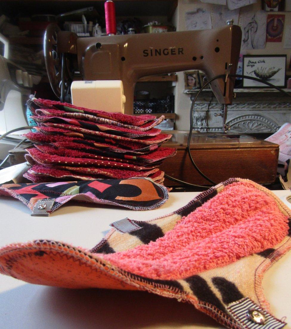 A stack of reusable menstrual pads in front of a sewing machine