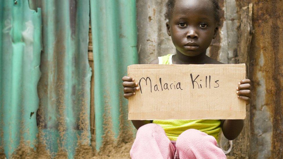 girl holding a sign saying 'malaria kills'