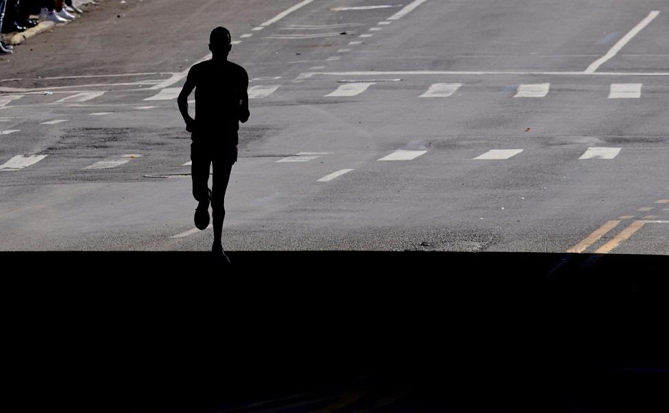 Kenya's Albert Korir is seen in silhouette as he runs under a bridge.