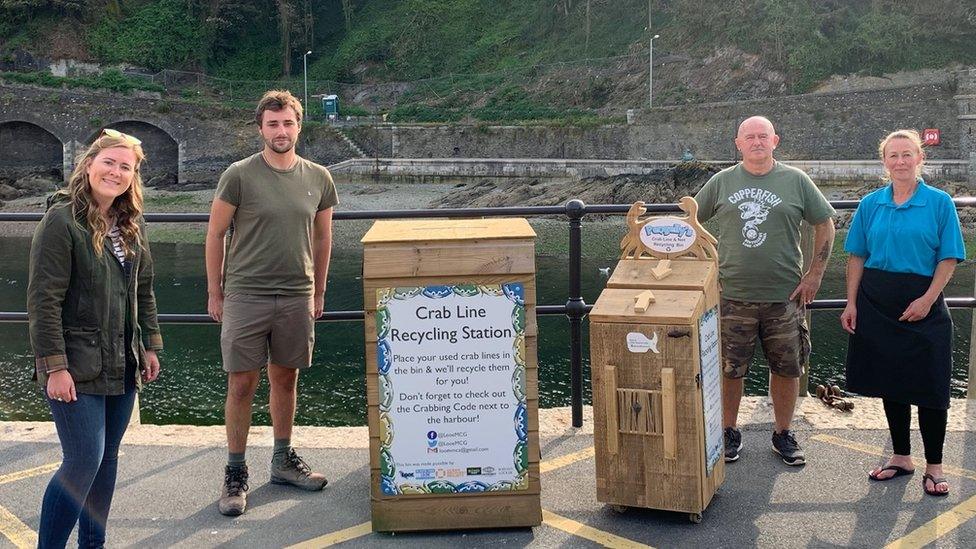 Amelia Bridges, Sam Gill, Pete Spencer, and Hayley Phillips stand next to the recycling boxes