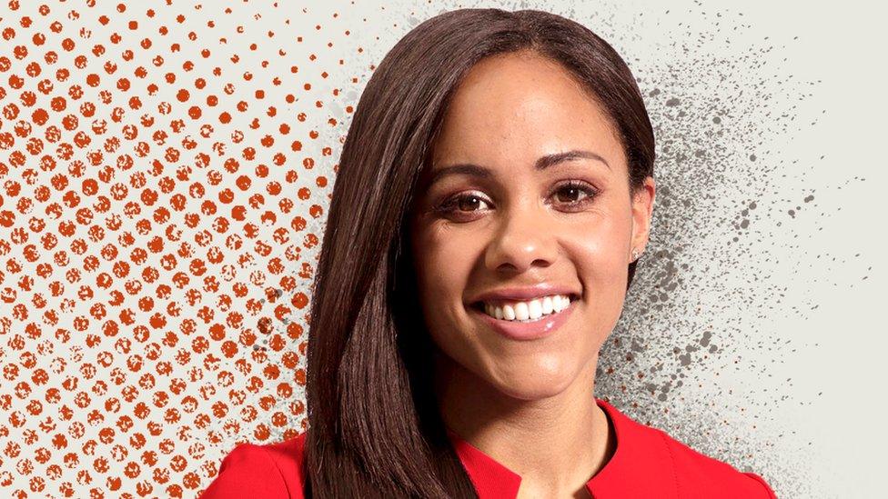 Alex-scott-in-a-red-dress-smiling-in-front-of-a-white-background