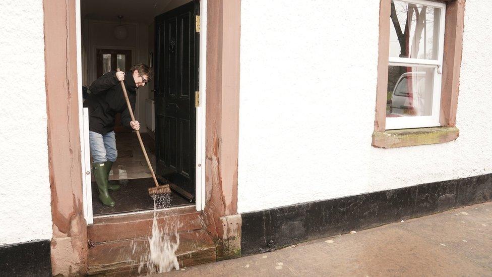 Karen sweeps water out of her home