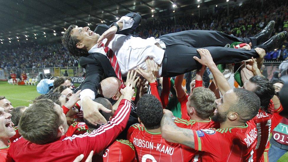 Players lift Wales' head coach Chris Coleman into the air in celebration.