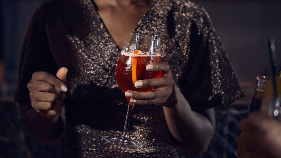 Stock image of a woman in a sparkly top holding a drink