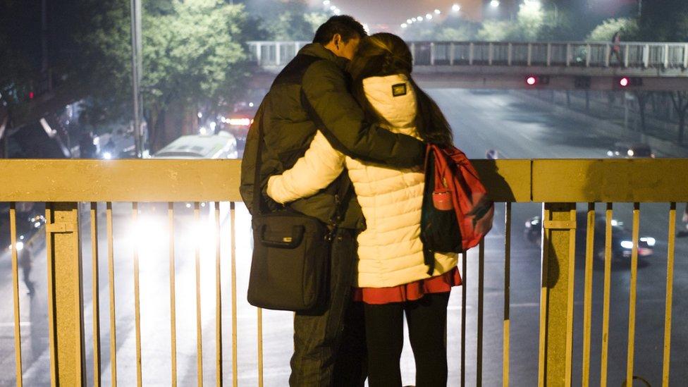 Couple embrace on a bridge