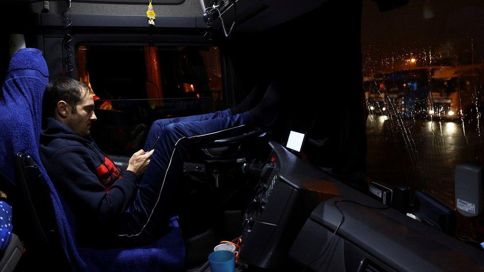 A Romanian driver rests inside his lorry at Ashford International Truck Stop