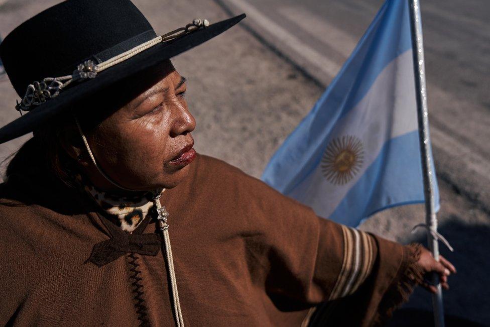 A woman holds an Argentine flag at the roadblock in Purmamarca, where indigenous communities demonstrate in defence of water and their land rights and against the controversial reform backed by Governor Morales, on June 28, 2023.