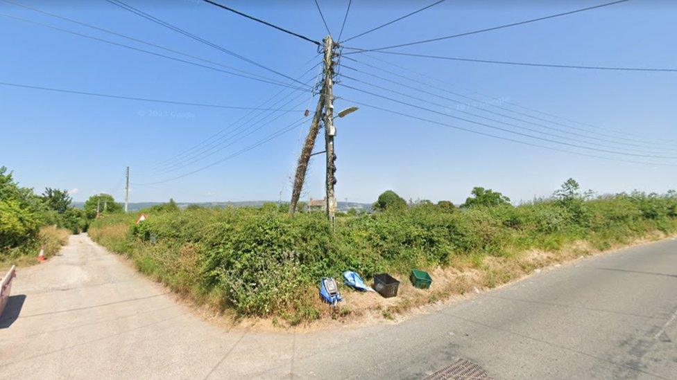 Street corner that would mark the edge of the site, with wooden telegraph pole in foreground.