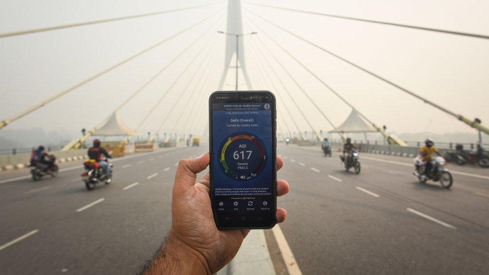 A smartphone showing the Air Quality Index app used in India to report pollution levels on a New Delhi bridge.