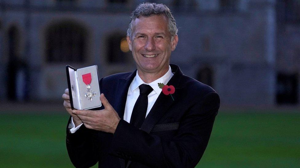 Adam Hills with award in hand