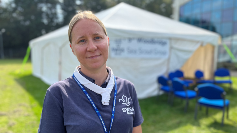 Nicola Tooke is wearing a scouts t-shirt, standing in front of a white marquee.