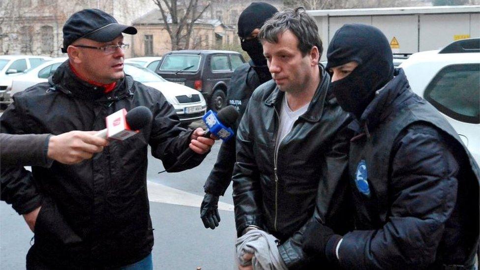 Marcel Lazar Lehel is escorted by masked policemen in Bucharest, after being arrested on 22 January, 2014.