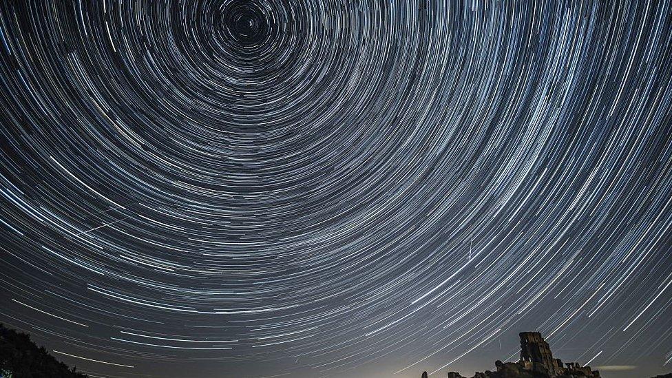 A long exposure shot of a meteor shower has produced streaks of white lines in a circle in the night sky