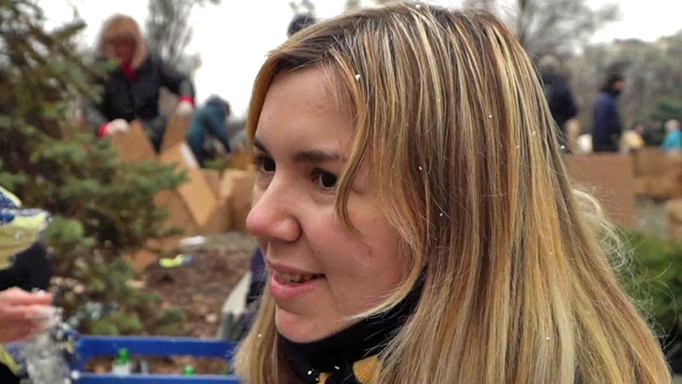 Arina sits with other women, preparing Molotov cocktails. She is dusted with white polystyrene chunks that are a component of the bottle-bombs