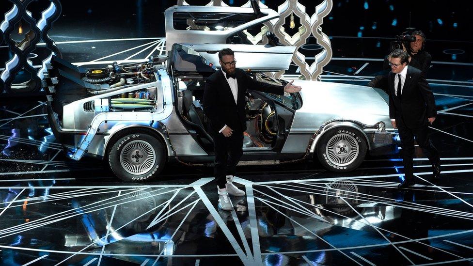 Seth Rogen (left) and Michael J. Fox step out of a DeLorean onstage