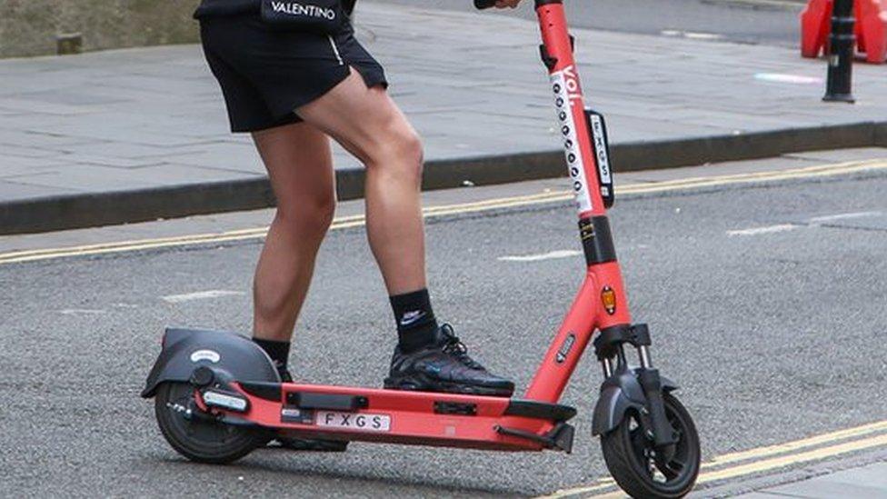 A man riding a Voi scooter