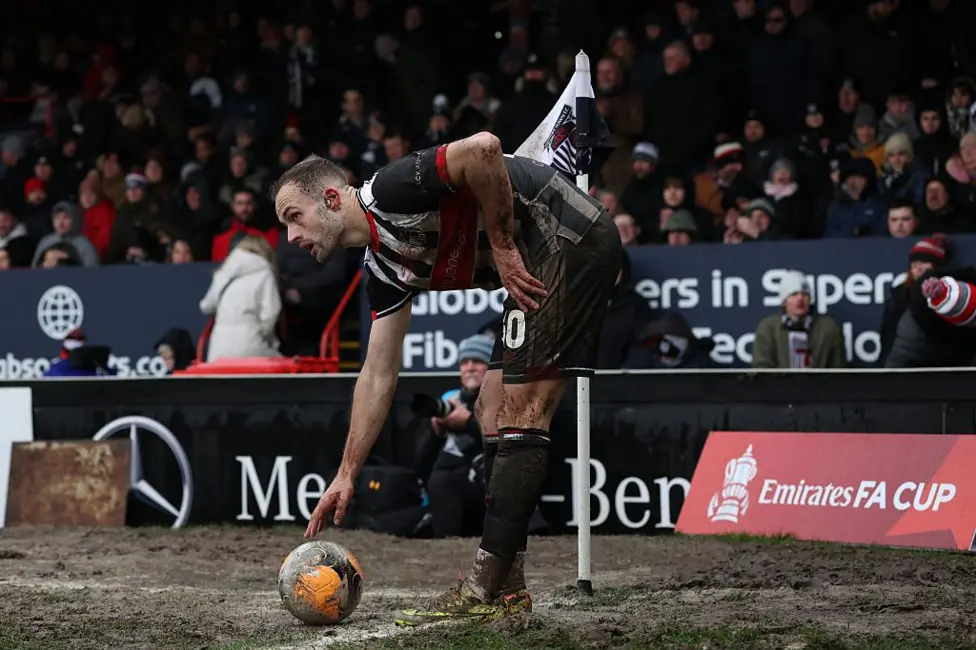 Grimsby midfielder Charles Vernam, covered in mud, prepares to take a corner