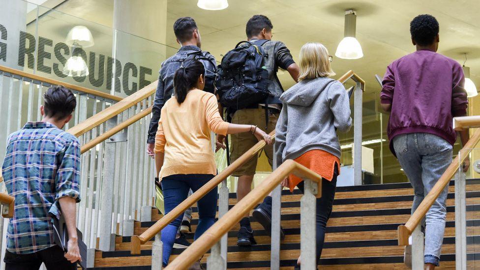 A group of students walk up a staircase in a university.