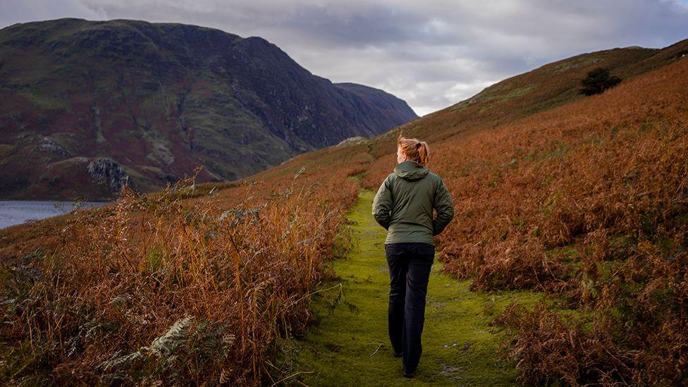 Red haired anonymous woman walks outside in rural UK setting