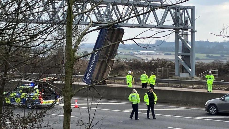 Image of police officers on the M5 inspecting the lorry bed, wedged under a gantry