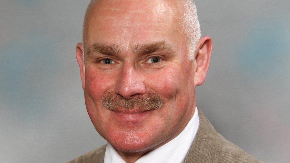 Alex Stevenson smiles towards the camera in an official portrait as a councillor