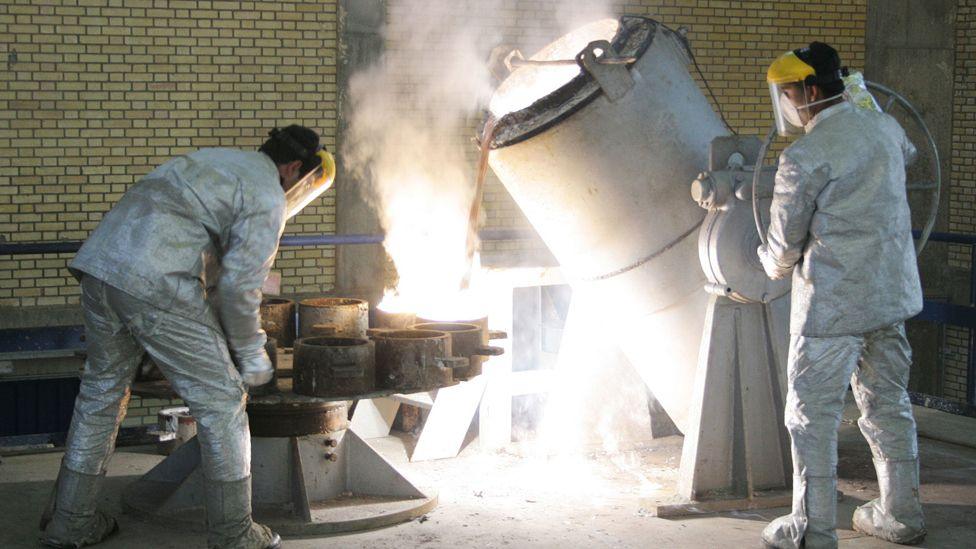 Technicians work inside of a uranium conversion facility, appearing in white overalls and pouring liquids into containers, on 30 March 2005 just outside the city of Isfahan, Iran