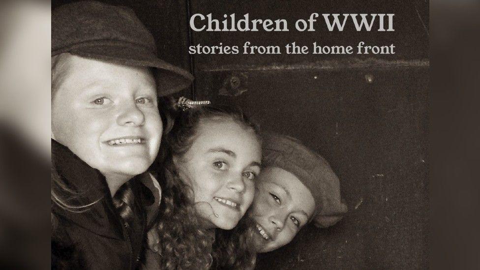 Black and white image of three children, two boys and a girl acting in an Anderson Shelter.