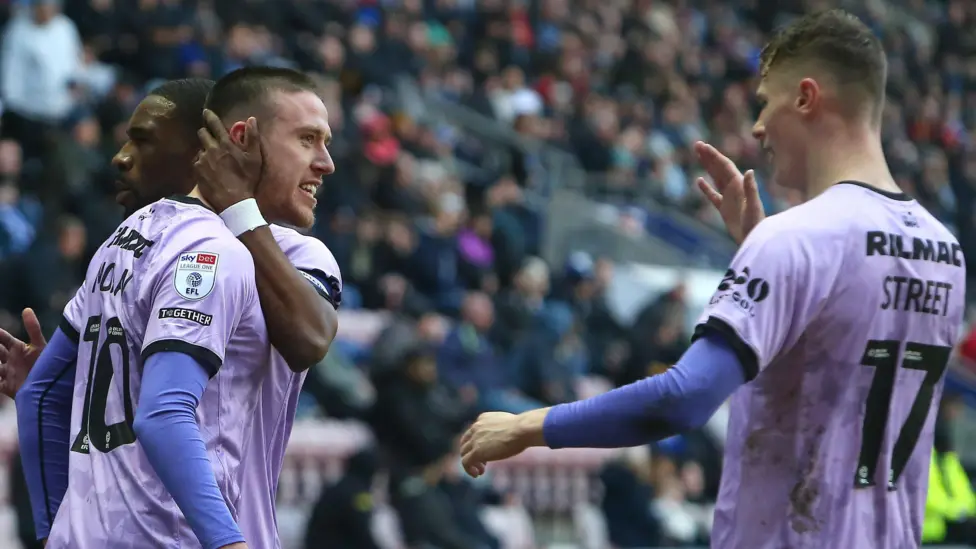 Jack Moylan anotó el único gol justo después de la mitad del primer tiempo para mantener a Lincoln en camino al ascenso automático a la Liga Uno gracias a la victoria ante el Wigan, que estaba en apuros. Jack Moylan anotó el único gol justo después de la mitad del primer tiempo para mantener a Lincoln en camino al ascenso automático a la Liga Uno gracias a la victoria ante el Wigan, que estaba en apuros.